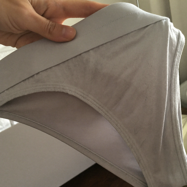 Gros plan sur la ceinture plate d'une culotte gris perle tenue à la main